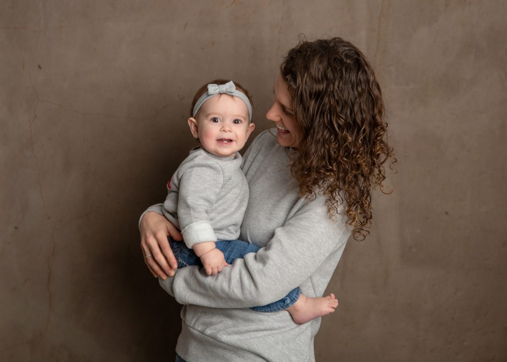 studio milestone portrait of mama and baby dressed in gray and denim baby plan